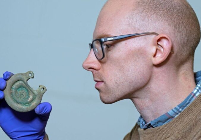 Curator Dr Matthew Knight examining a bronze object from the Peebles Hoard. Credit: Neil Hanna.