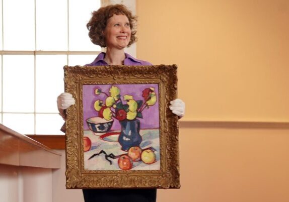 Alice Strang with the  S.J. Peploe painting. Credit: Lyon & Turnbull/Stewart Attwood